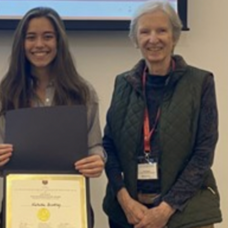 a young woman with long brown hair holding a certificate standing next to an older woman with short grey hair